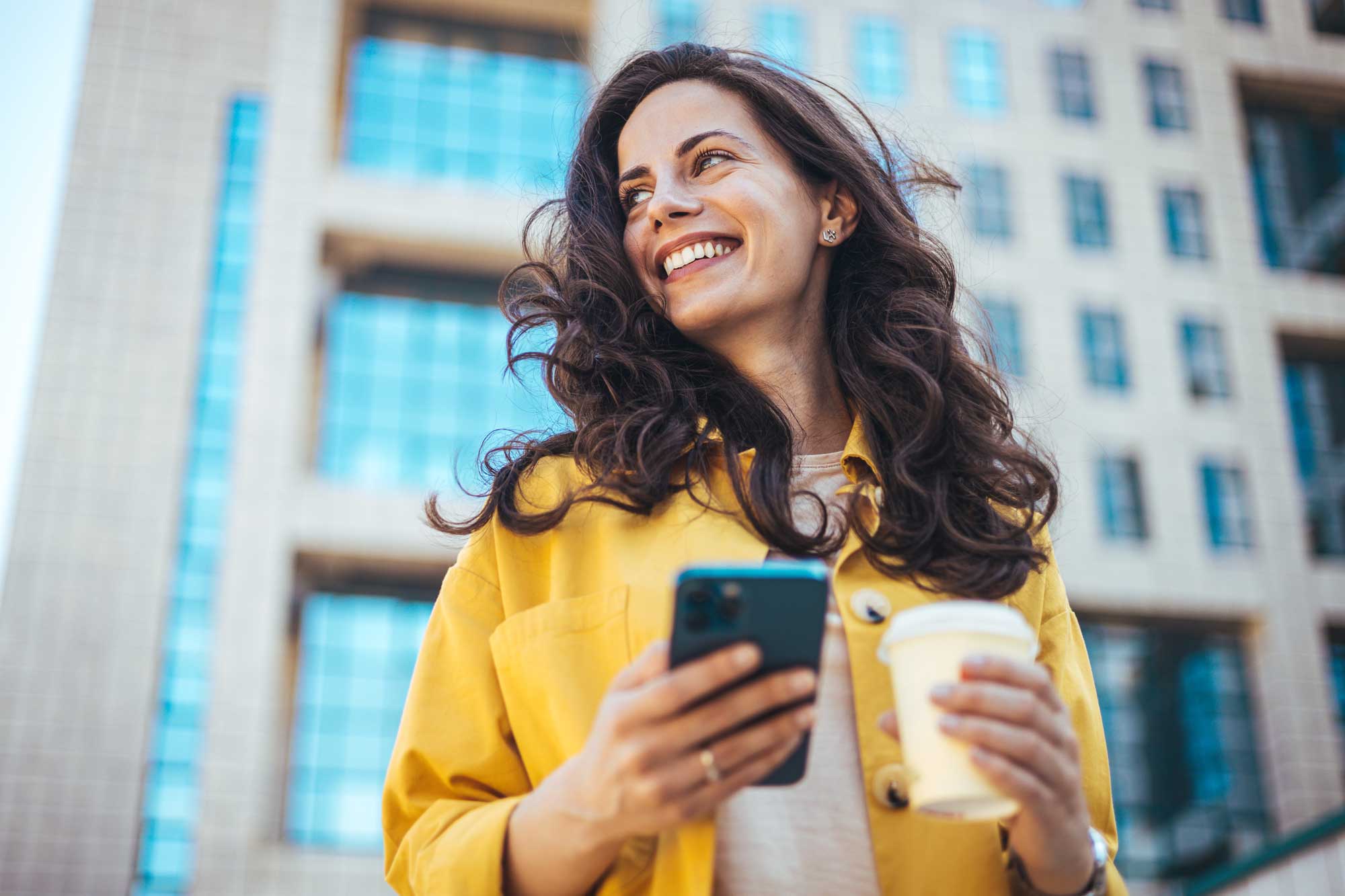Junge Frau grinsend mit Smartphone in der Hand
