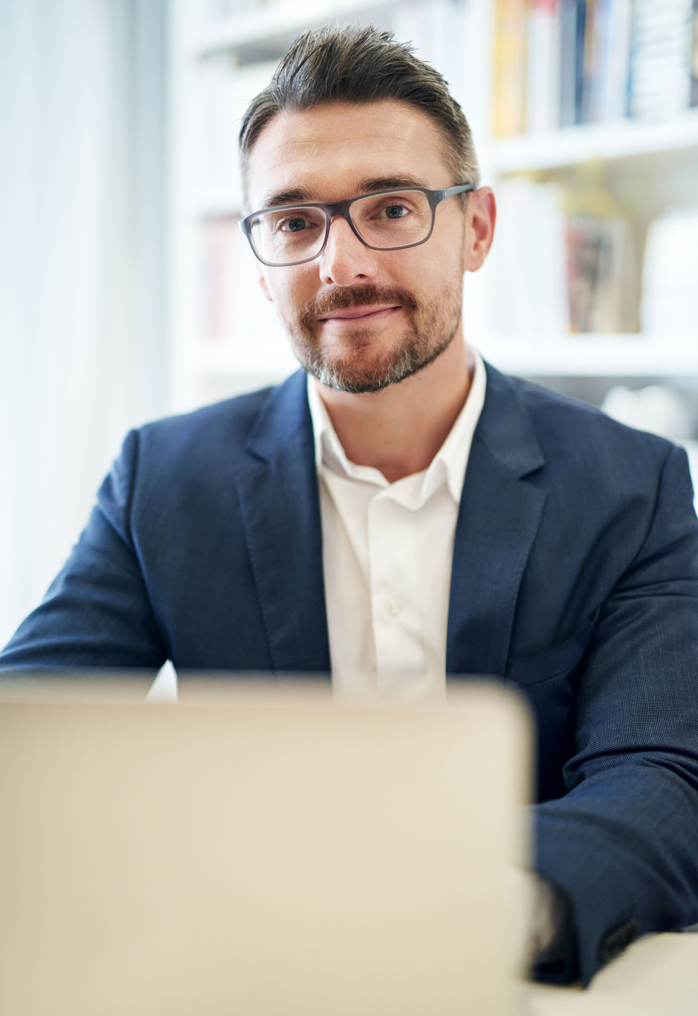 Teammitglied der KKU, ein Webdesigner vor seinem Laptop, in die Kamera schauend